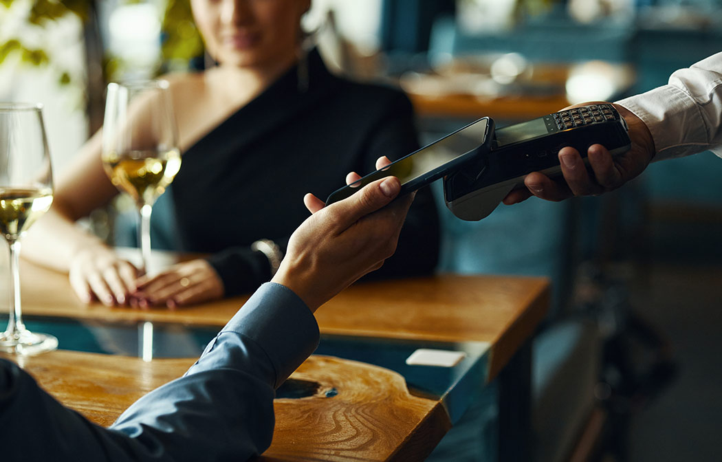 Uomo elegante paga con lo smartphone in un locale