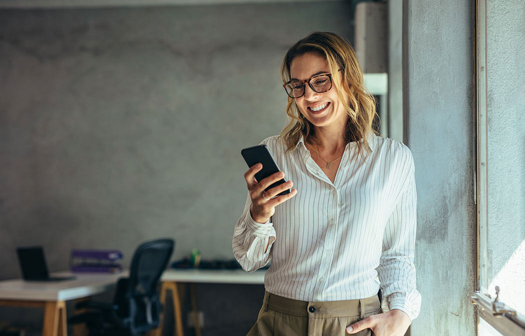 Smiling businesswoman using her phone in the office.